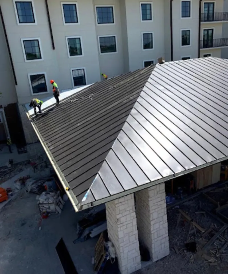 Crew installing standing seam metal roof panels on a commercial project in Pikeville